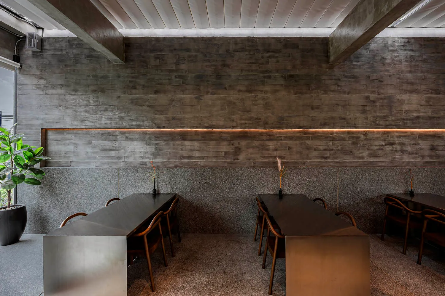 Elegant restaurant interior with stone walls, two dining tables, and multiple chairs, creating a sophisticated atmosphere