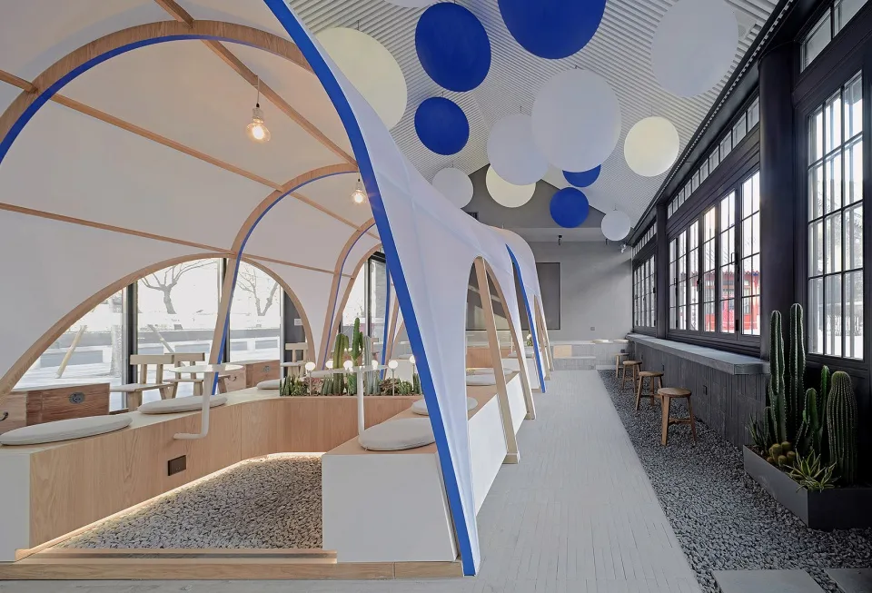 開放式餐廳內部，多張餐桌椅、盆栽植物，及天花板懸吊圓球