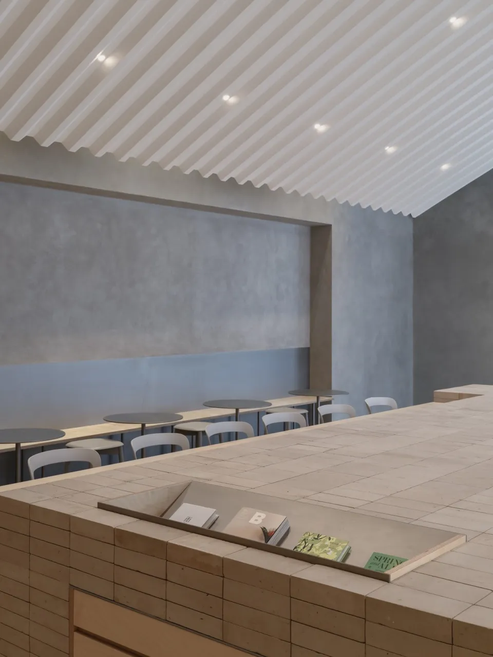 Cozy cafe interior with a counter and chairs, featuring a display of books and a warm atmosphere
