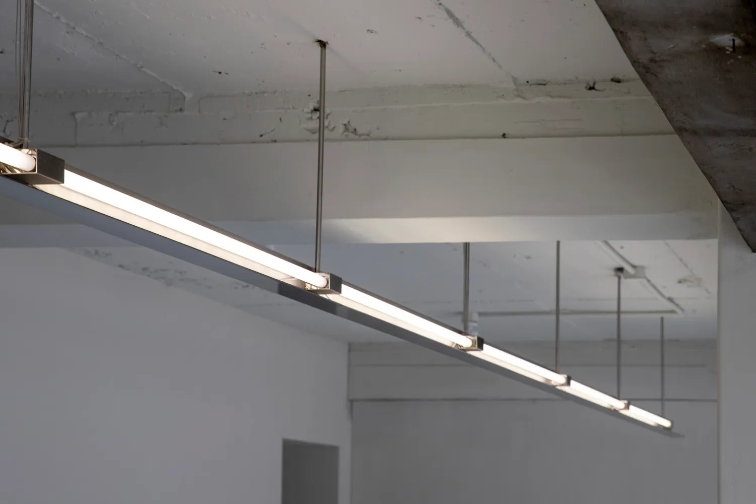 A bright and modern hallway with a long white corridor and lights hanging from the ceiling