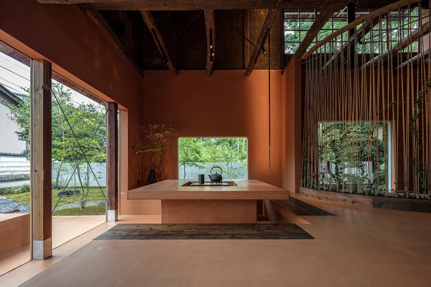 木質地板餐廳，配有大型餐桌與兩盆盆栽，透過窗戶自然光線照亮