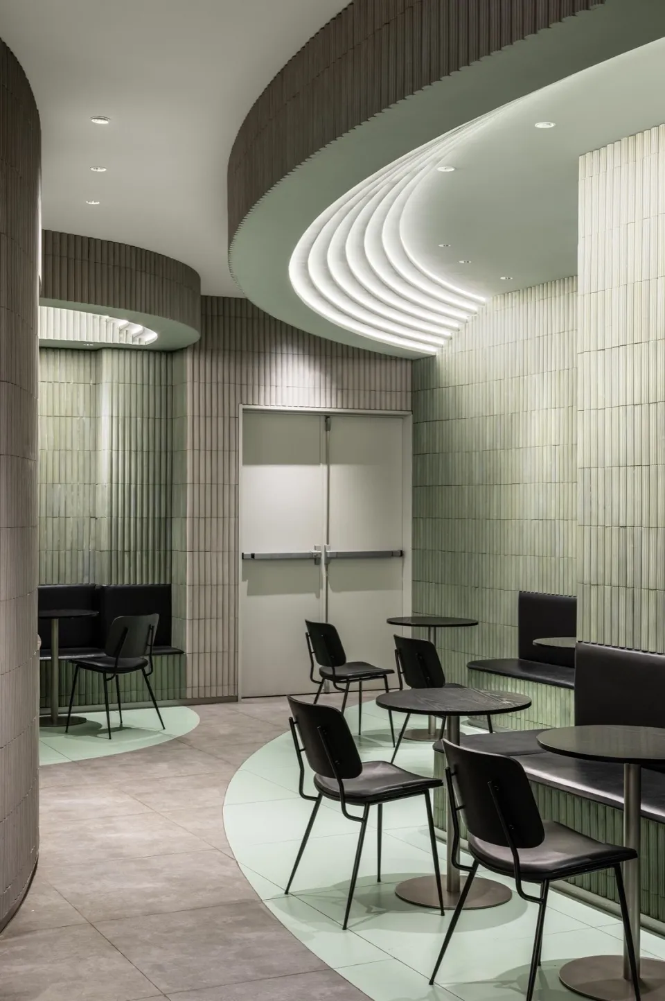 A restaurant interior with multiple tables and chairs, green tile walls, and a welcoming atmosphere