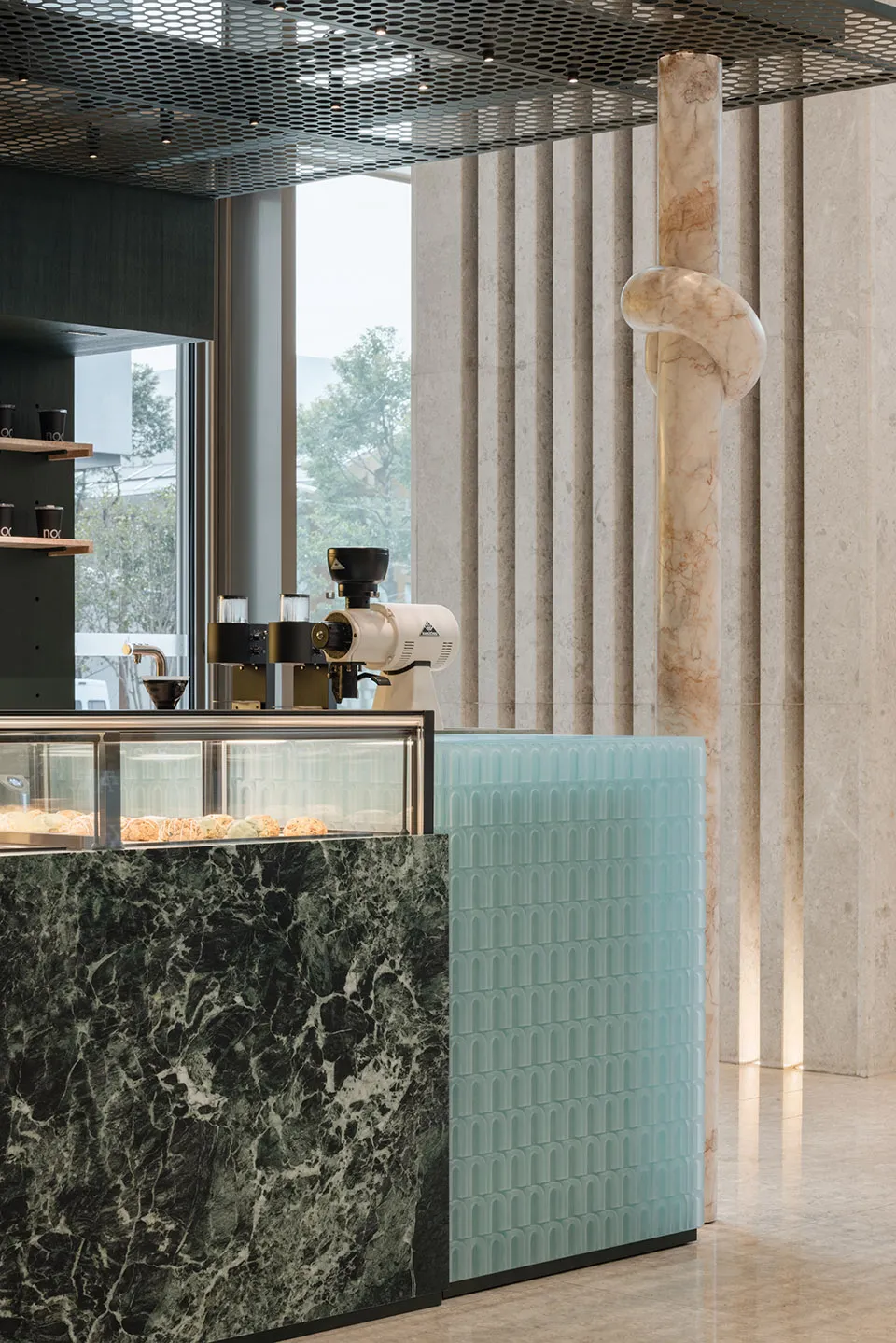 A well-organized coffee shop with a marble countertop, display case, and modern appliances