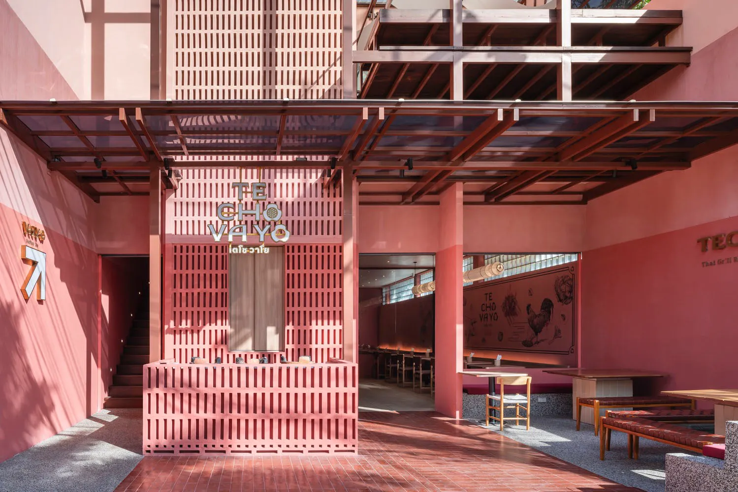 Cozy modern restaurant with pink walls, a large window, and chairs around a dining table