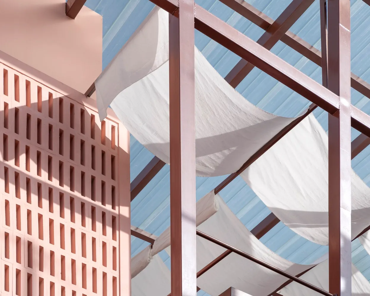 A modern building with a large white fabric canopy, clean lines, and simple shapes, well-lit by natural sunlight