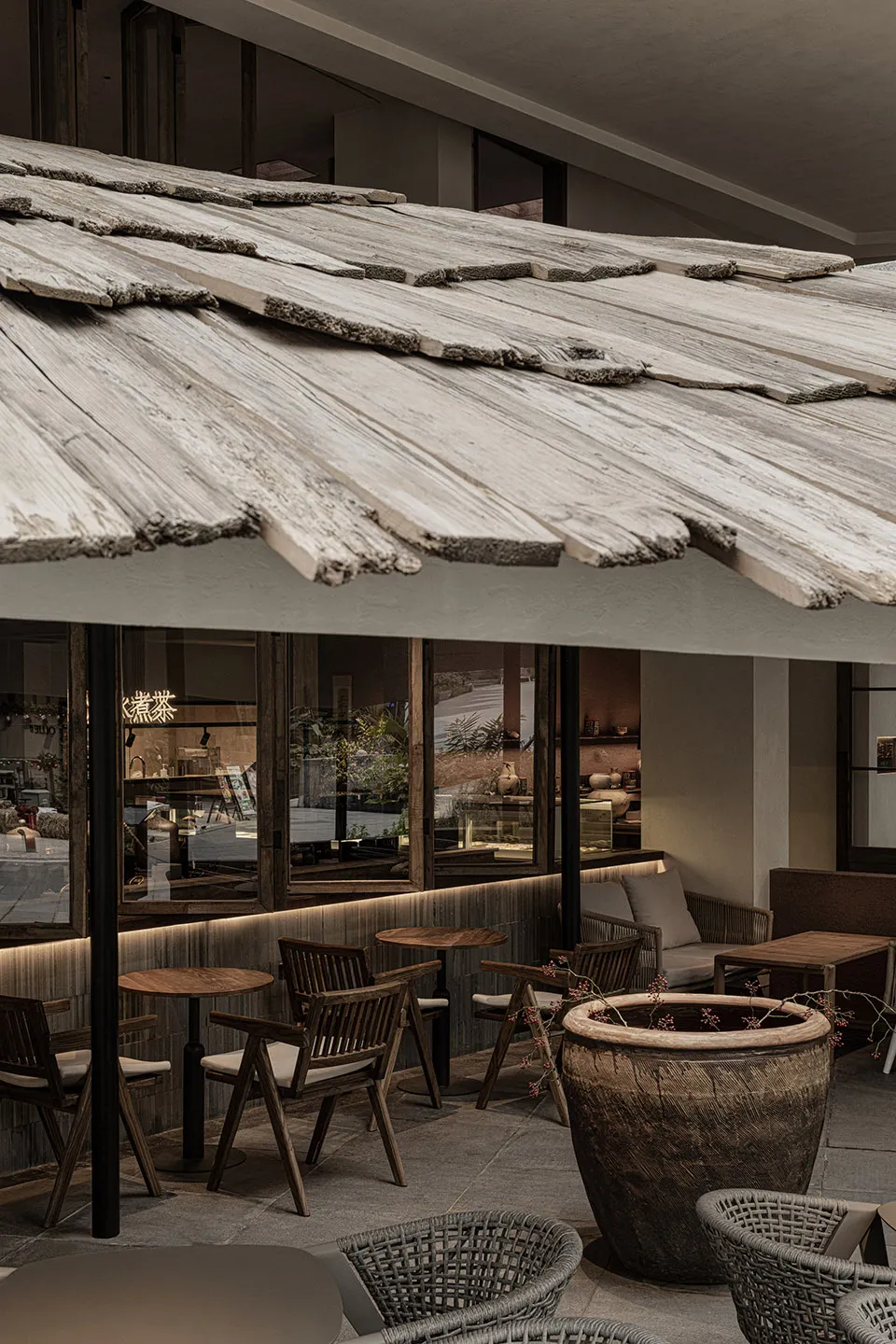 An open-air restaurant with wooden tables and chairs, surrounded by plants and natural elements, in a warm and inviting atmosphere with bright daytime lighting