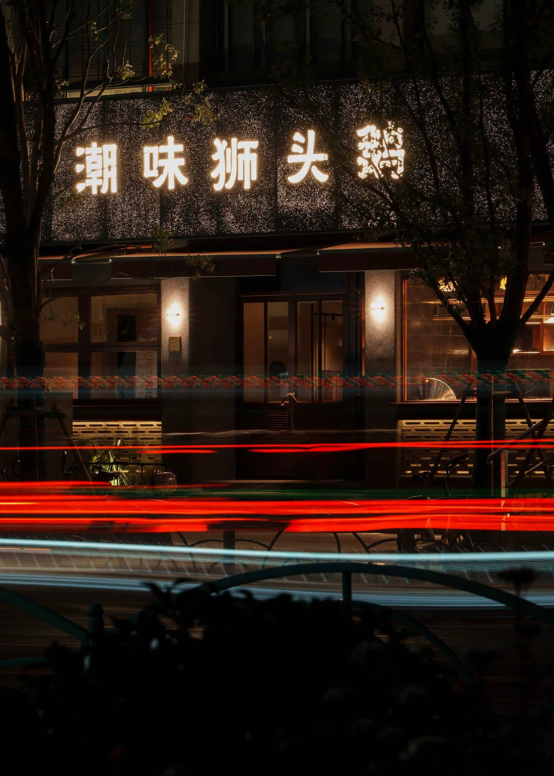 夜晚現代亞洲餐廳，點亮的招牌、餐桌與椅子，溫暖燈光照亮