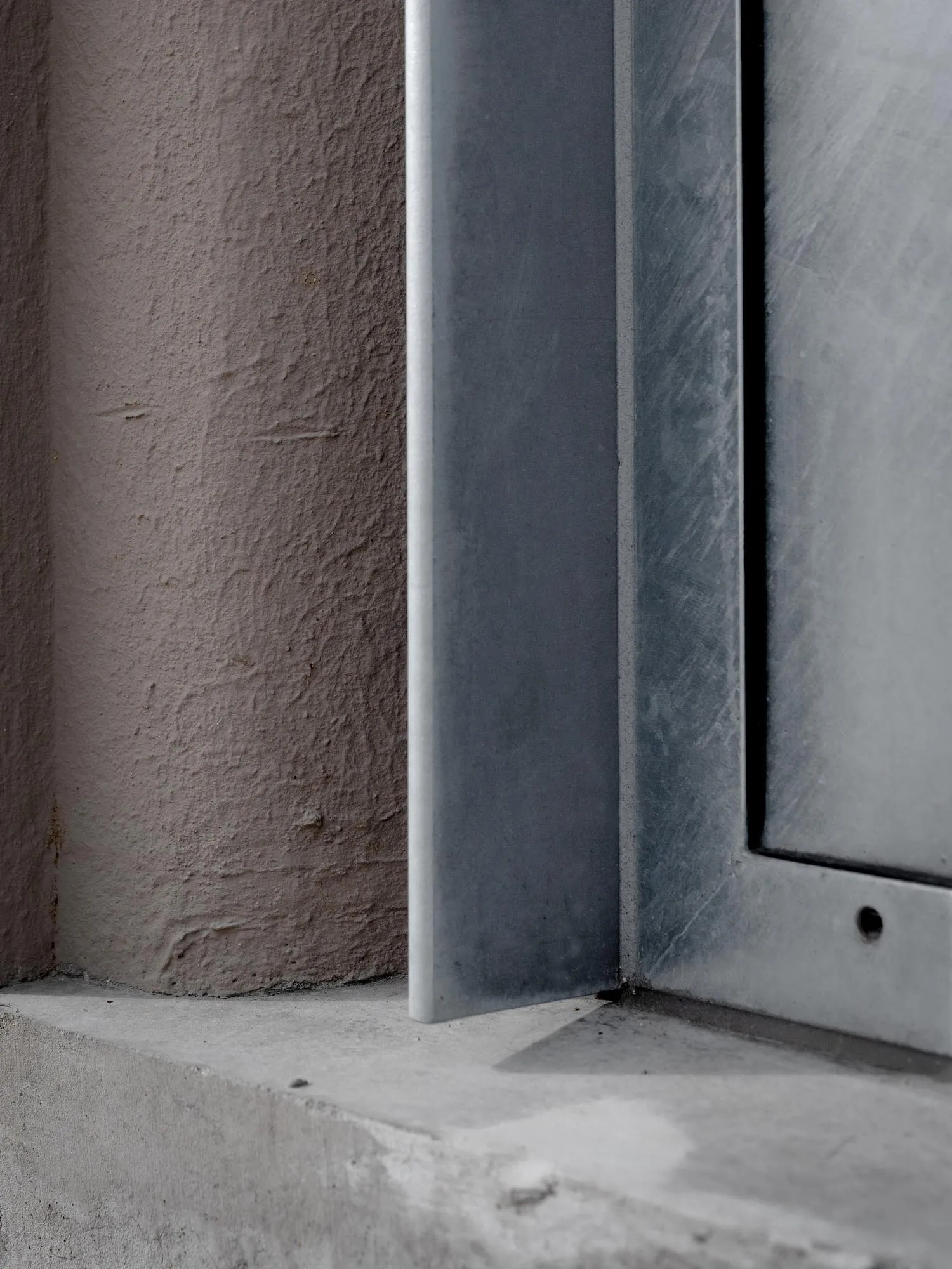 A building facade with a grey metal window frame, set against a neutral background