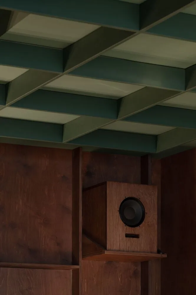 A wooden cabinet with a brown finish and open door, containing two speakers, in a home or office space