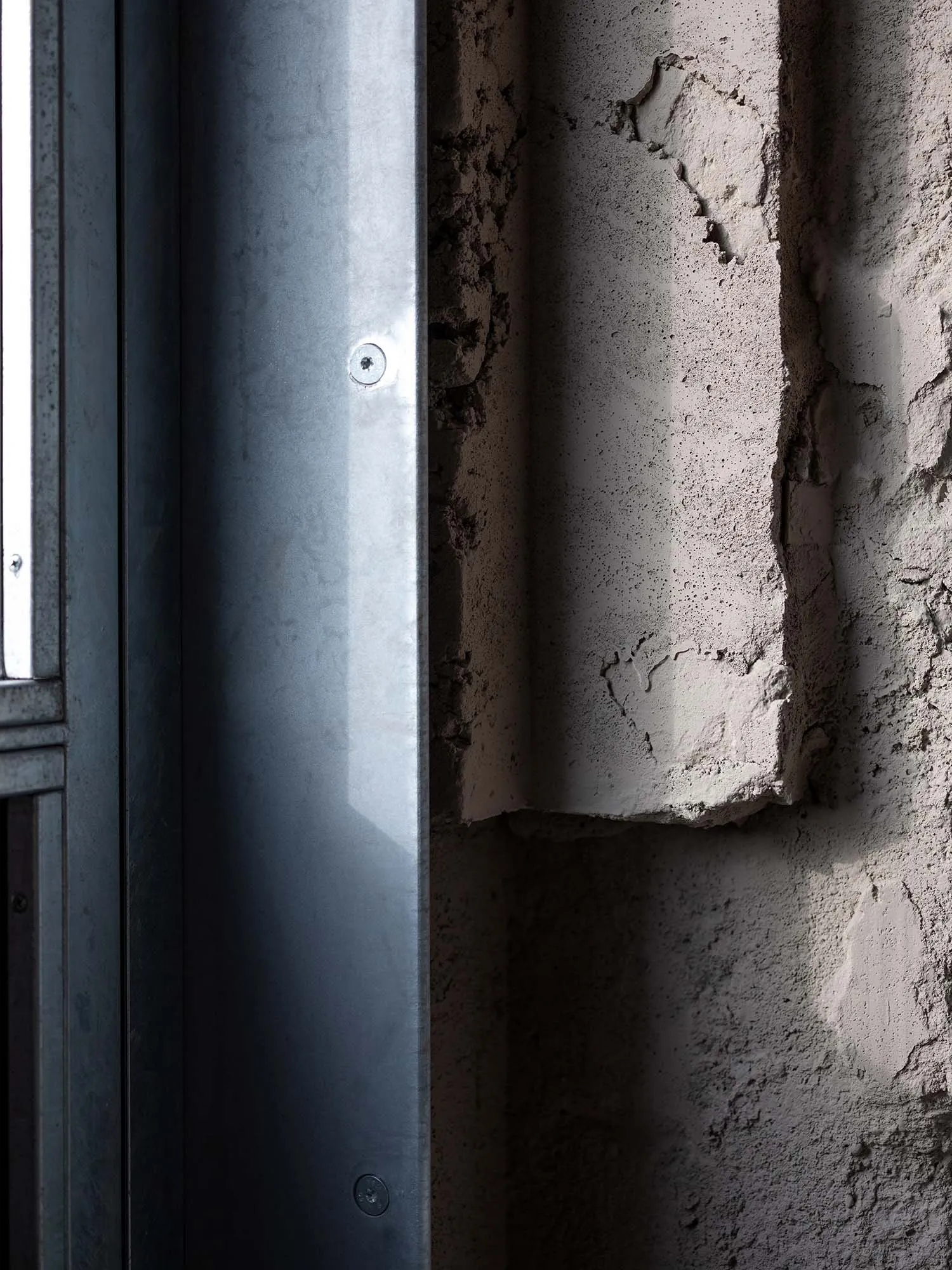 A dimly lit indoor space with a rusty metal pipe and concrete walls, featuring gray and brown colors