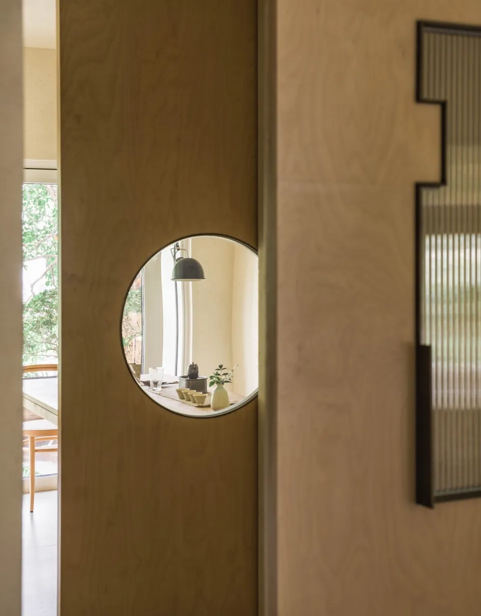 Interior design featuring a wooden wall with a large mirror and potted plants, surrounded by vases and decorative elements