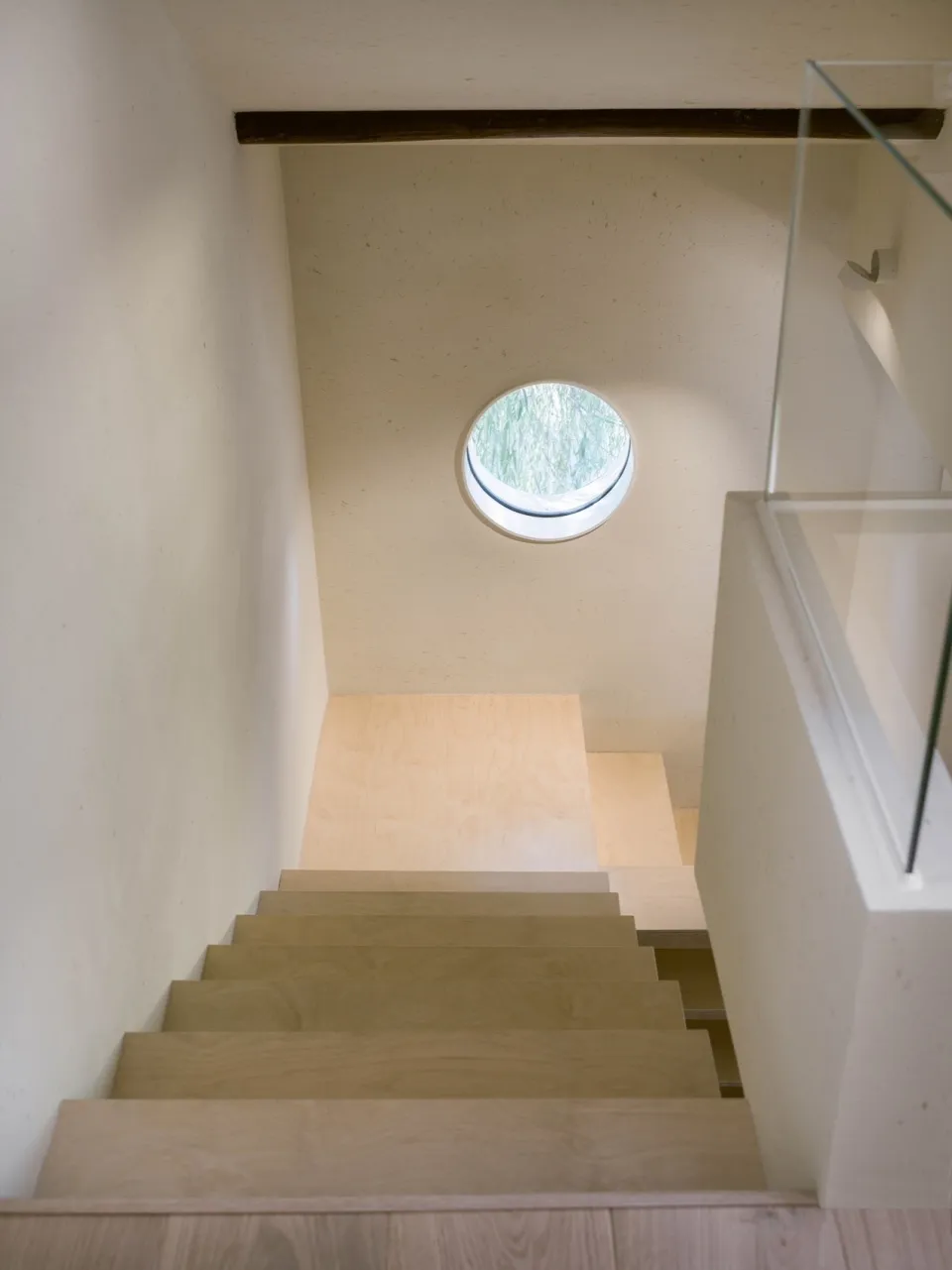 A real photo of a wooden staircase with a window at the bottom, providing natural light and a sense of depth and dimension