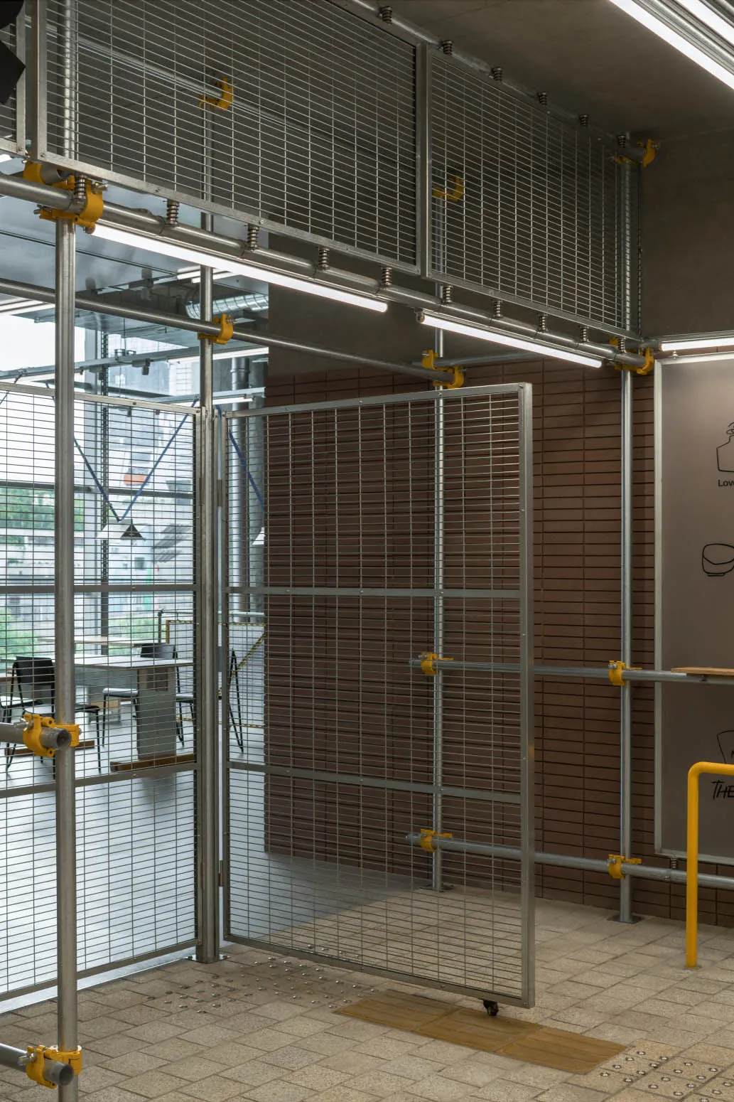 Industrial workspace with metal gate, chairs, and a dining table, giving off an impression of functionality and organization