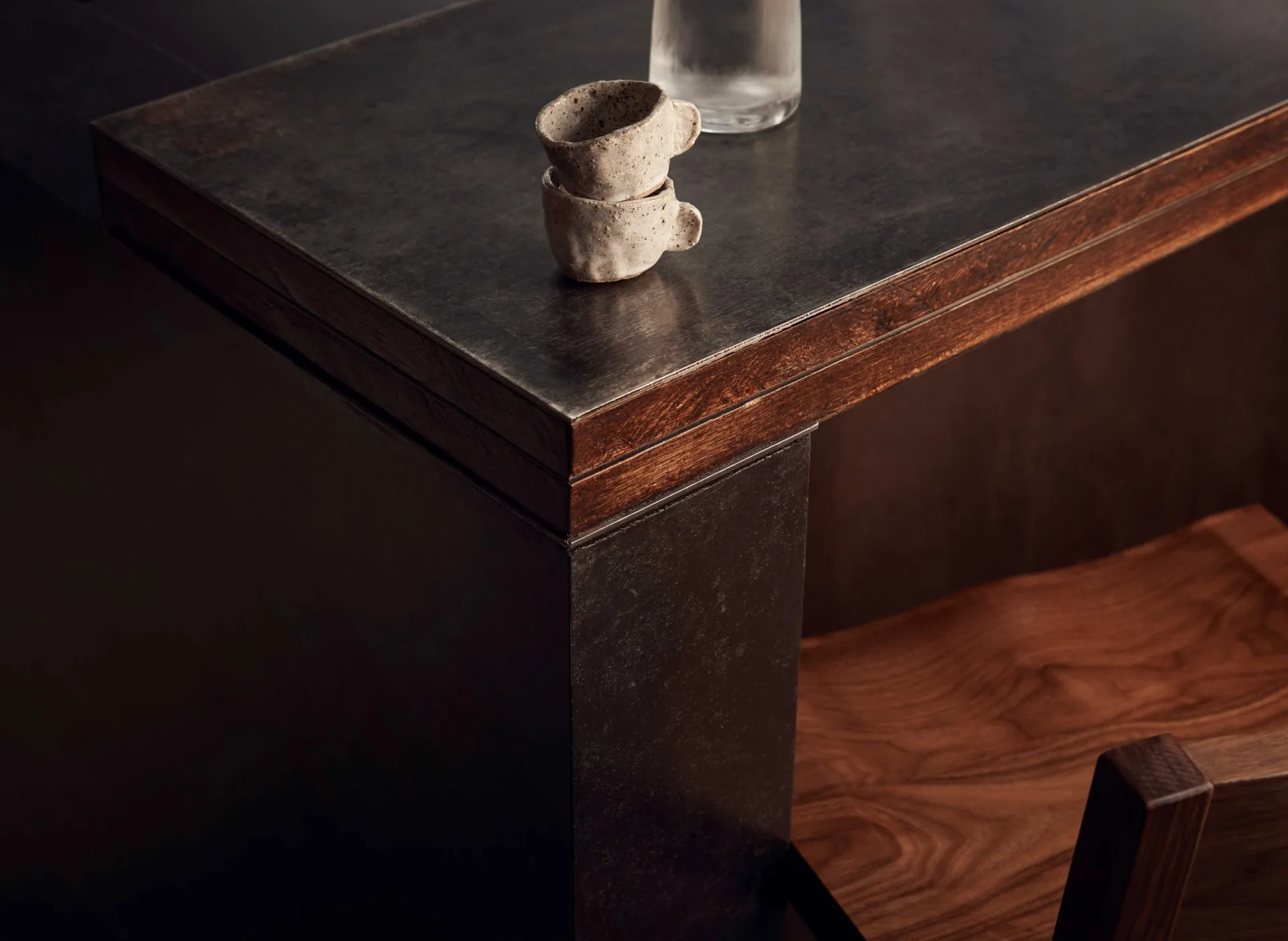 A wooden table with a black countertop features two cups and a bottle, set in a cozy and inviting space