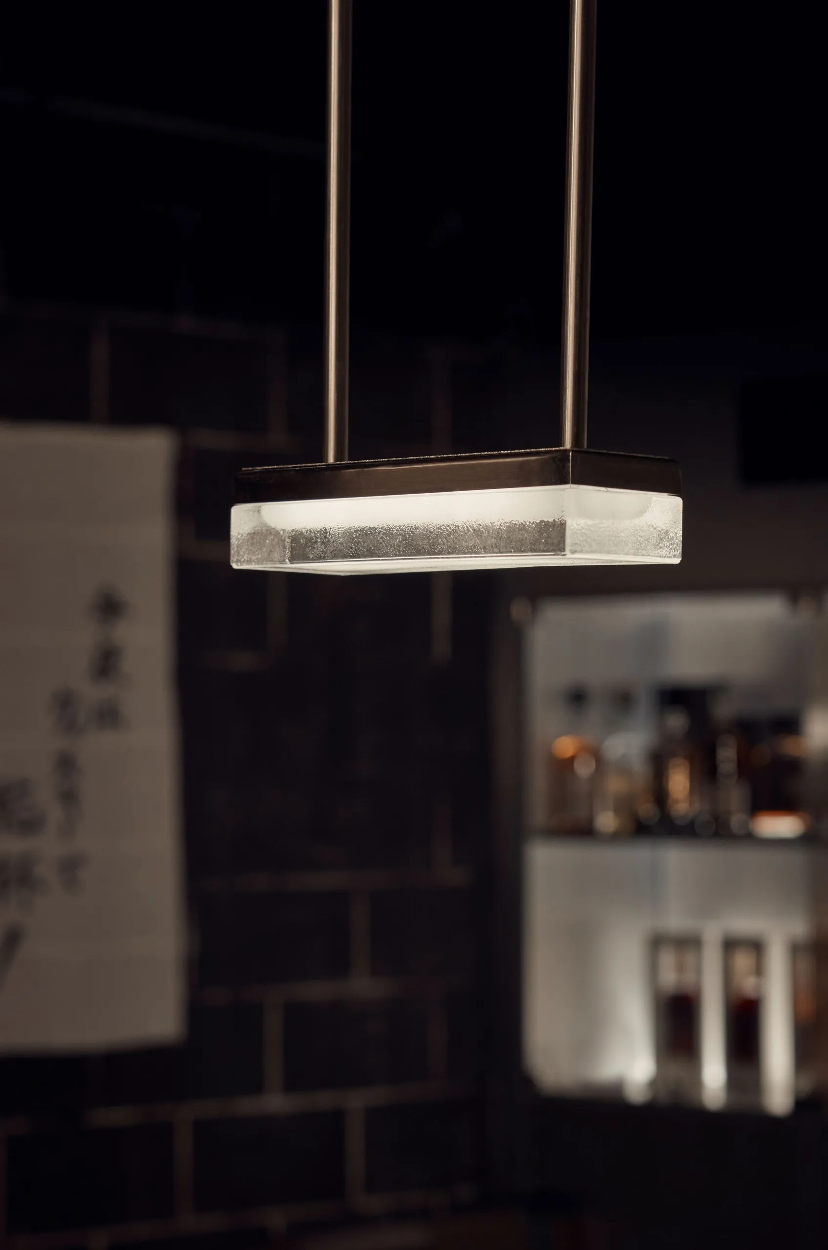 現代客廳空間，配有玻璃燈具、黑色磁磚牆與白色牆面，擺放裝飾瓶子，營造時尚氛圍