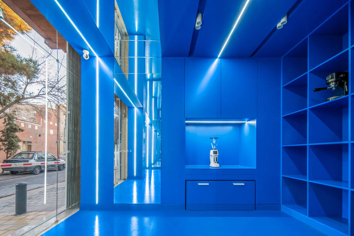 Modern kitchen with a blue theme, large window, sleek design, refrigerator, sink, and two ovens