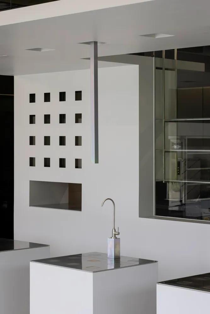 Modern kitchen with a wall-mounted sink, metal sink, and nearby bottles, set in a well-lit space