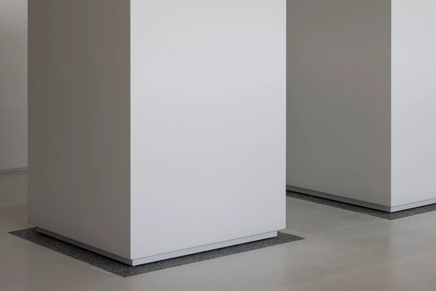 Empty white room with a large concrete wall, minimalist and serene atmosphere