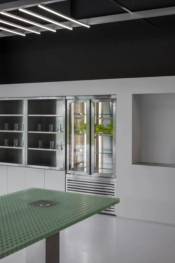 Modern kitchen with a stainless steel refrigerator, a table, and lined up cups on the countertop