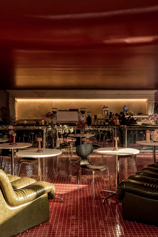 A warm and inviting restaurant interior with red walls, dining tables, chairs, and potted plants