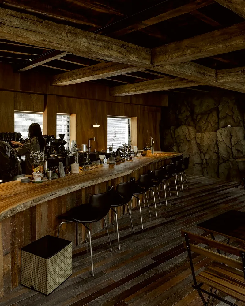 Modern bar area with a wooden countertop, stools, and chairs, creating a warm and inviting atmosphere
