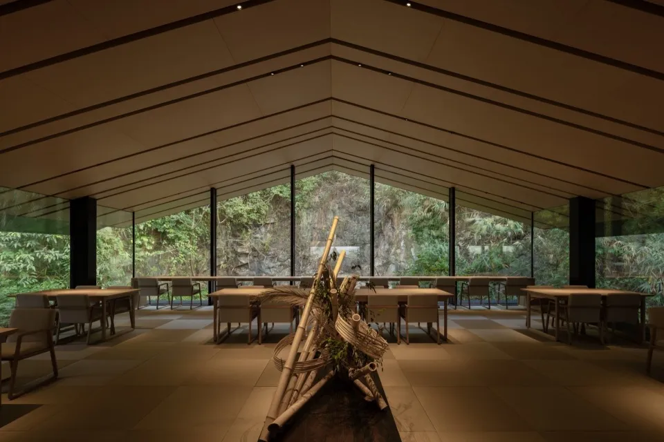 Open modern restaurant interior with tables, chairs, potted plants, and artwork on the walls