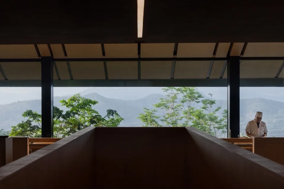 一座擁有木質外牆與大型窗戶的住宅，眺望山脈景觀，營造寧靜氛圍