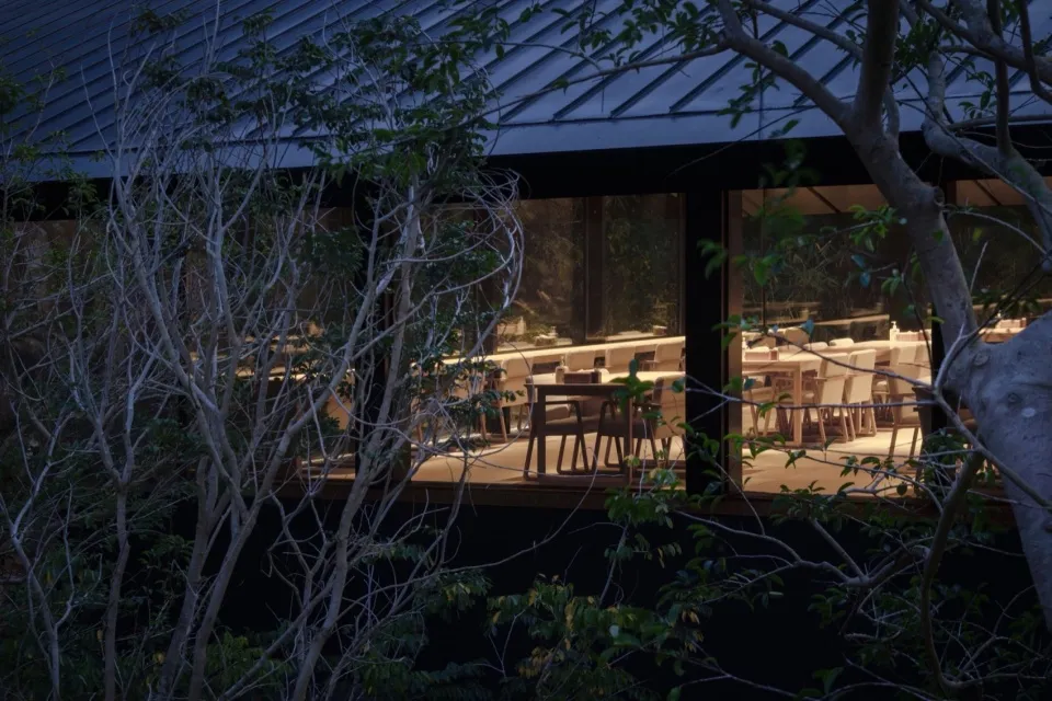 燈光柔和的餐廳用餐區，設有多張木質桌椅，營造溫暖舒適的氛圍