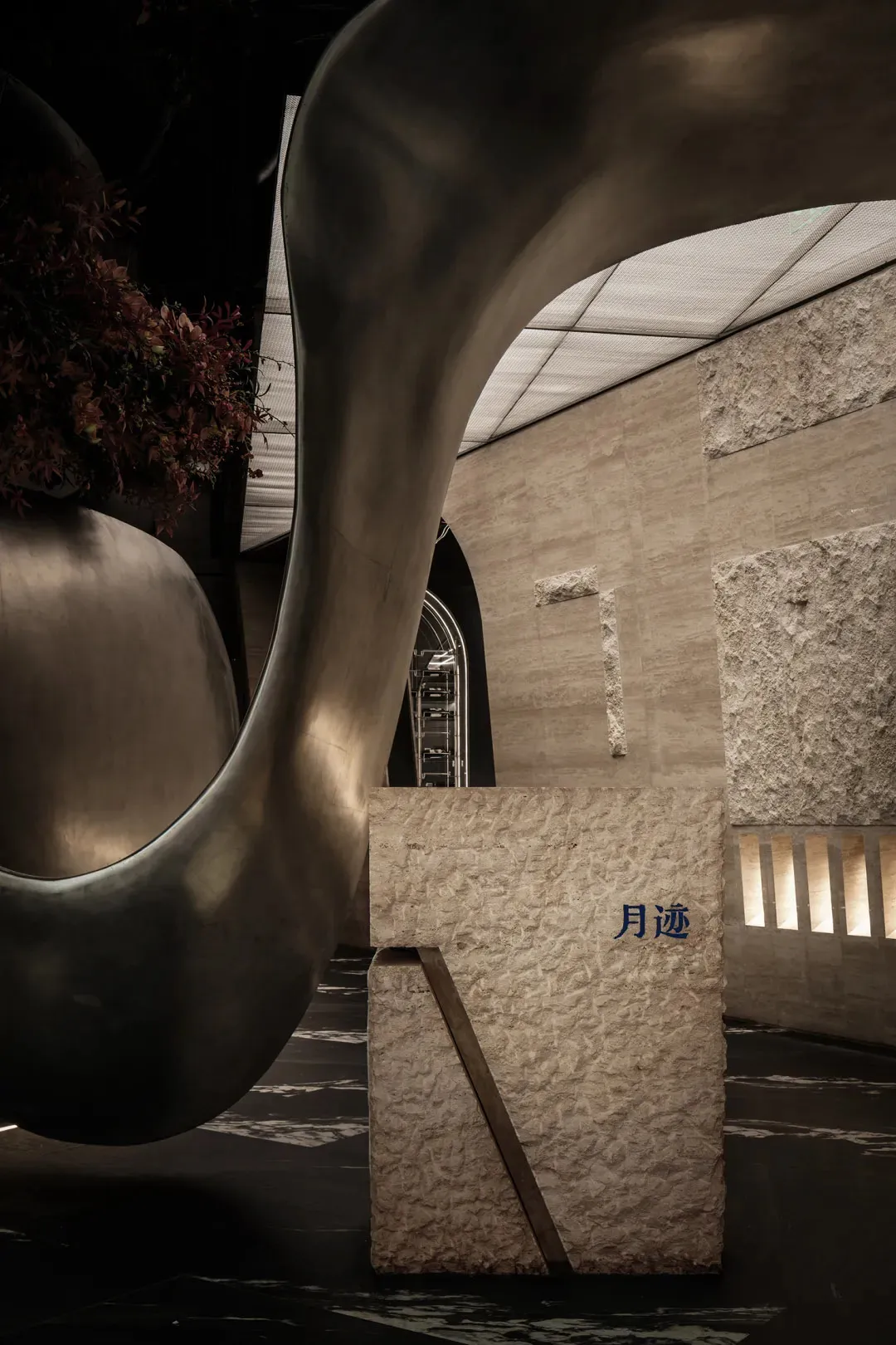 A modern interior space with a stone wall, a metal sculpture, and potted plants, conveying a contemporary and stylish atmosphere