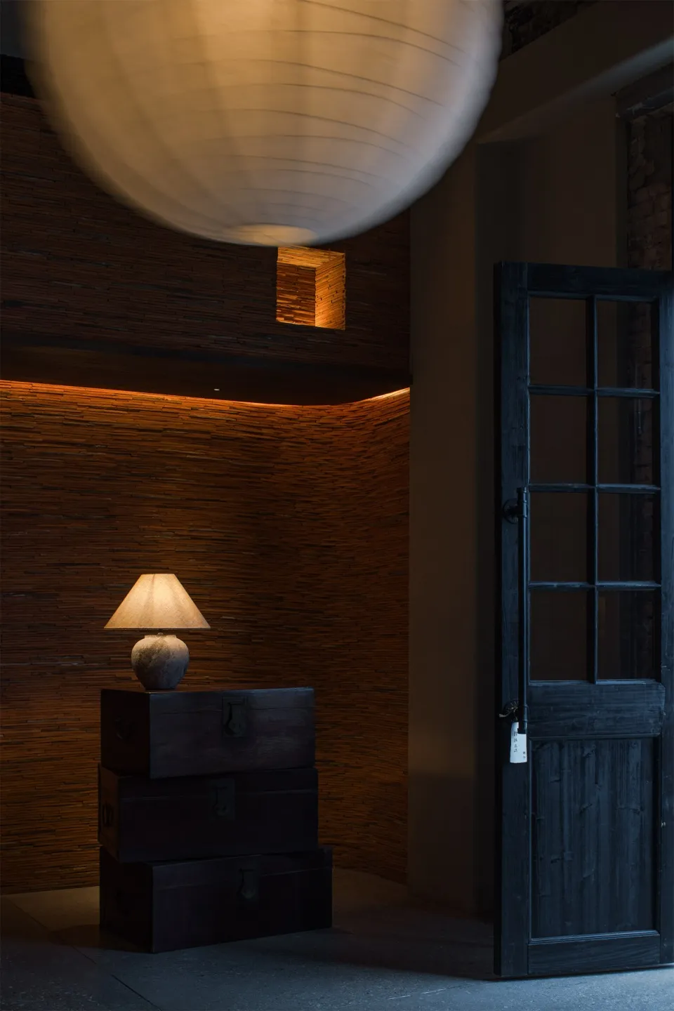 A wooden cabinet with multiple drawers and two lamps, a vase, and a warm atmosphere in a home office setting