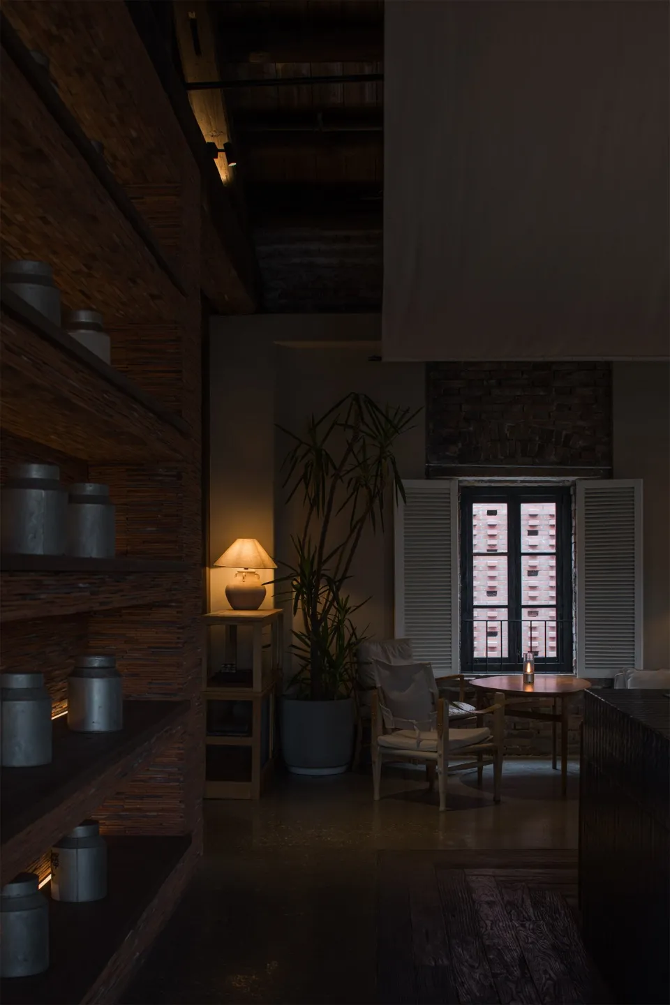 A well-lit living space with a dining table, chairs, potted plants, and vases on a wooden floor