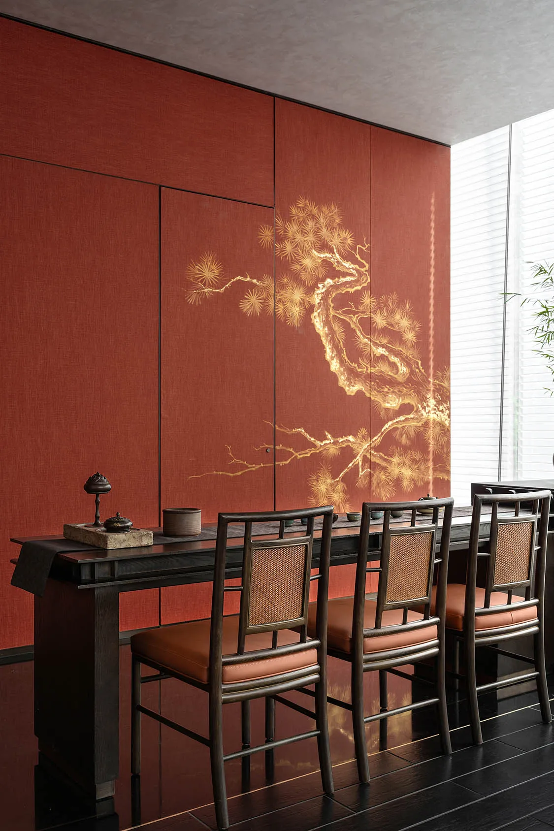 Dining area with red walls, a wooden table, and four chairs, featuring a vase and warm lighting