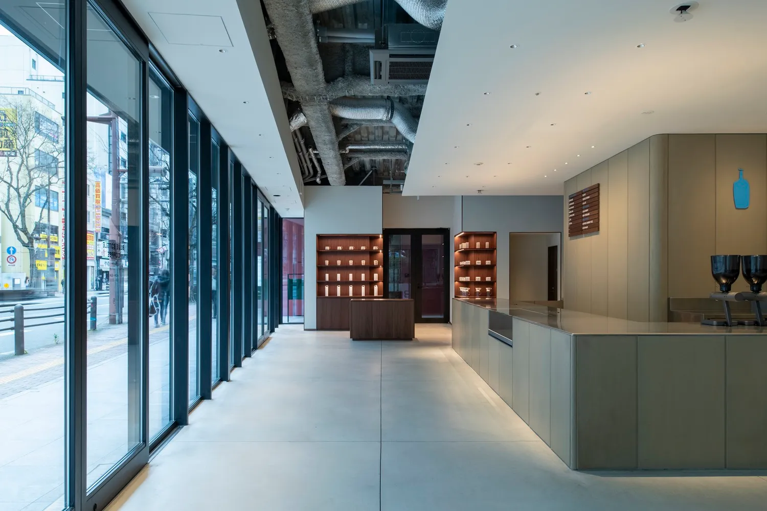 A bright and welcoming lobby with white walls, wooden accents, and natural light from a large window, featuring several people in a modern space