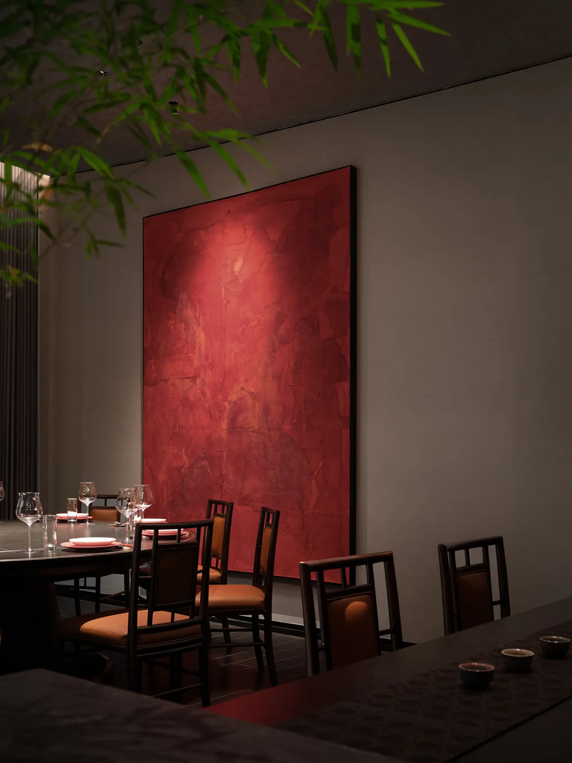 Warm and inviting dining area with a large red painting above a table, surrounded by multiple chairs