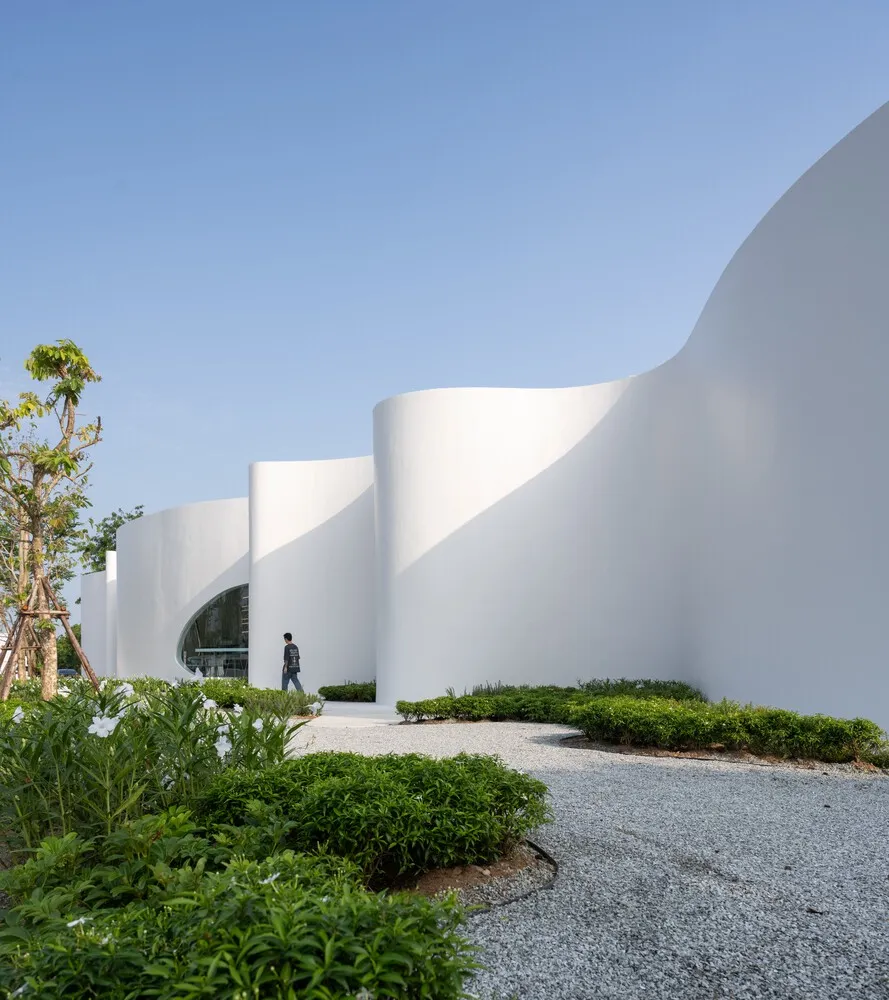 A large white building with curved walls and a circular entrance, set against a calm and inviting atmosphere