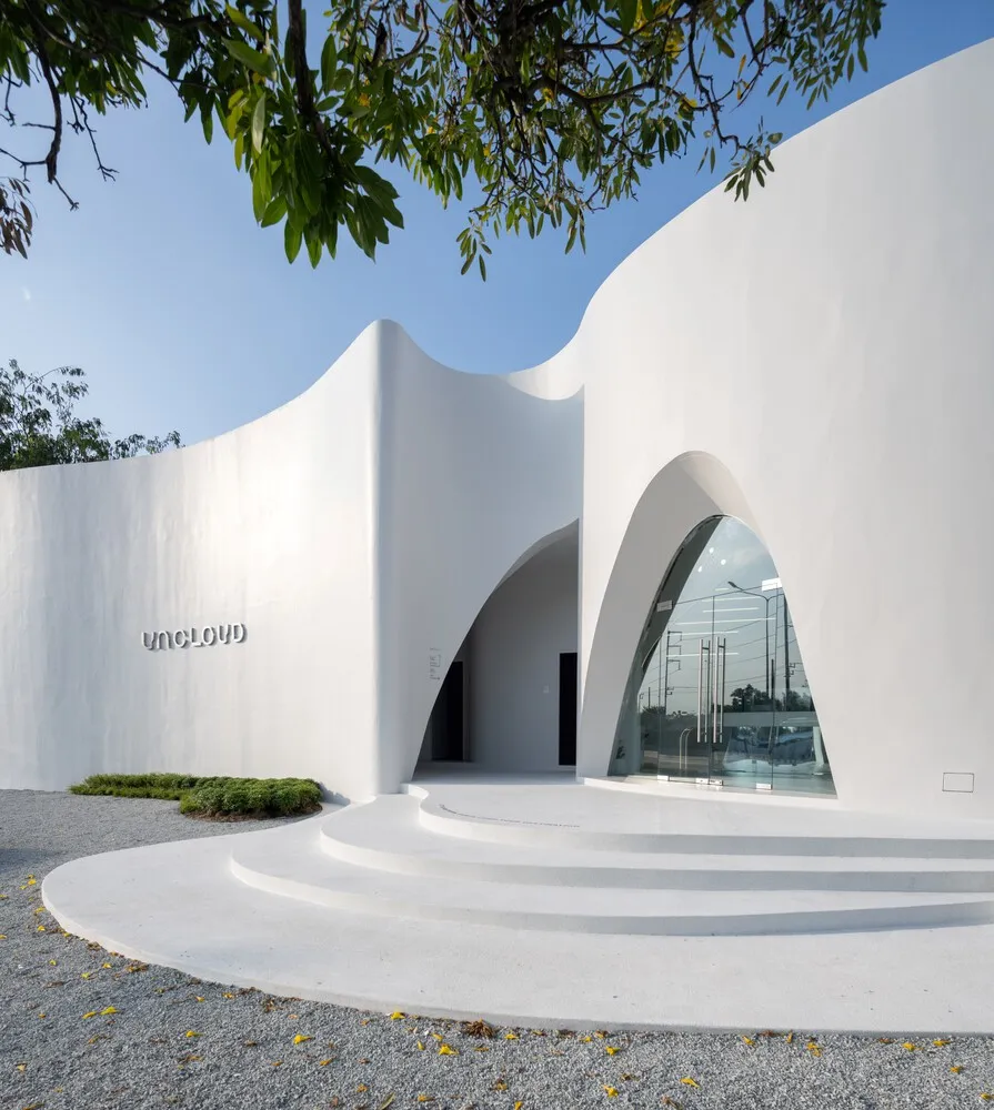Modern building with a white facade, a curved wall, and glass doors, set in a clean and minimalist environment