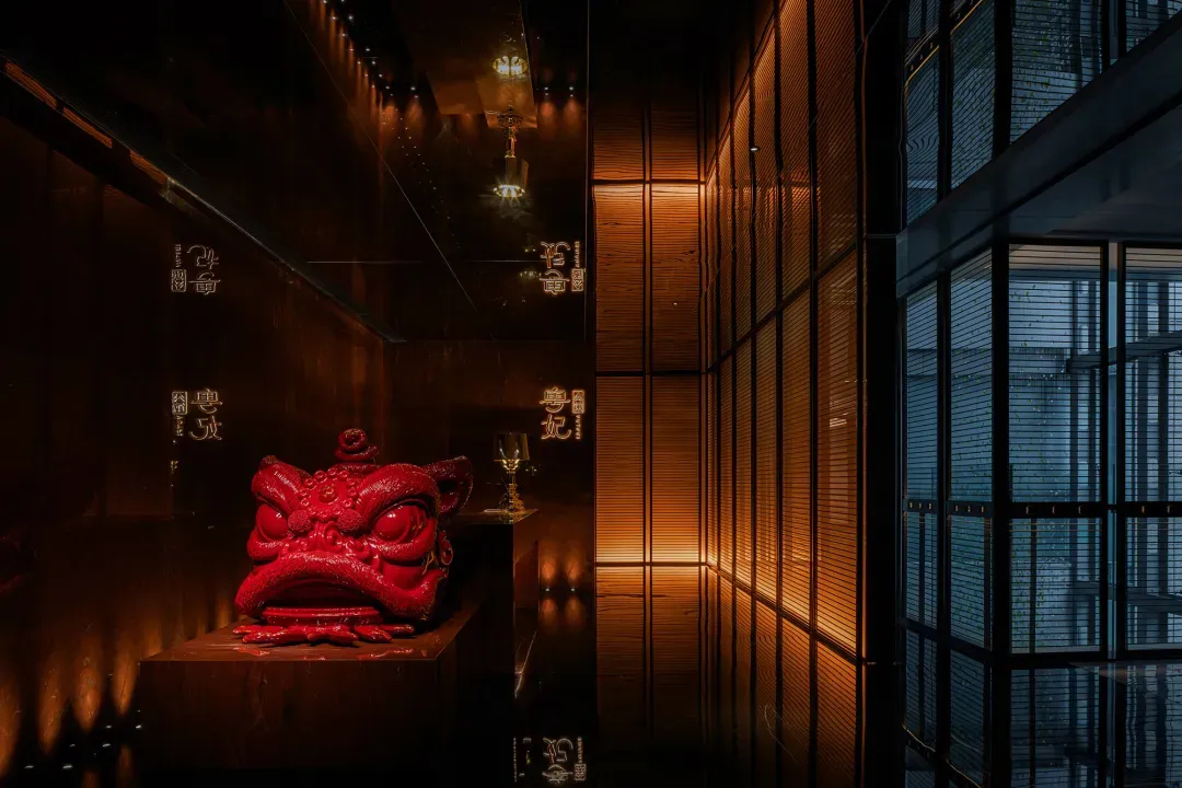 A dimly lit room with a wooden table, chairs, and an ornate red dragon statue as a centerpiece