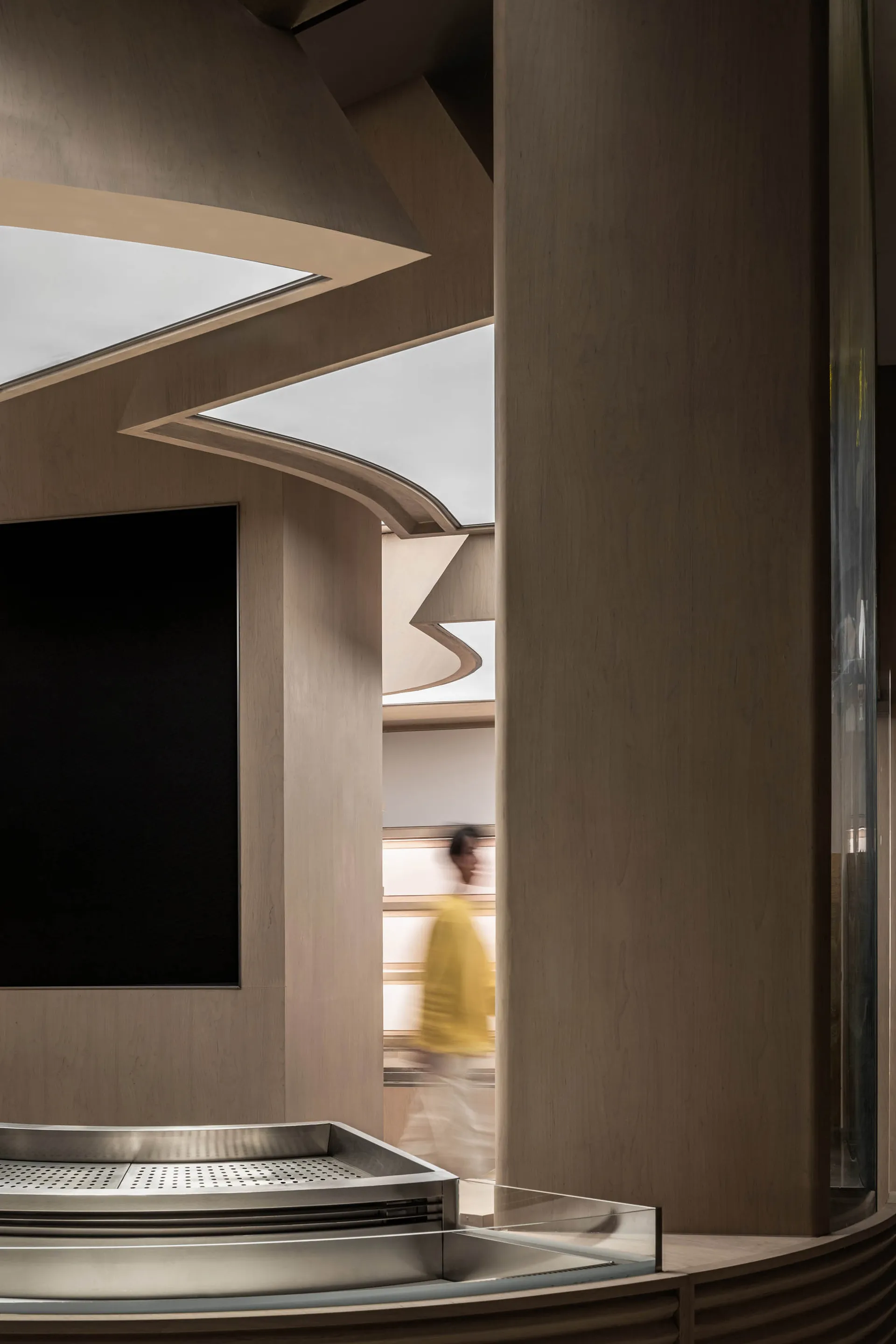 A man walks down a warm and inviting hallway with wooden walls and floors