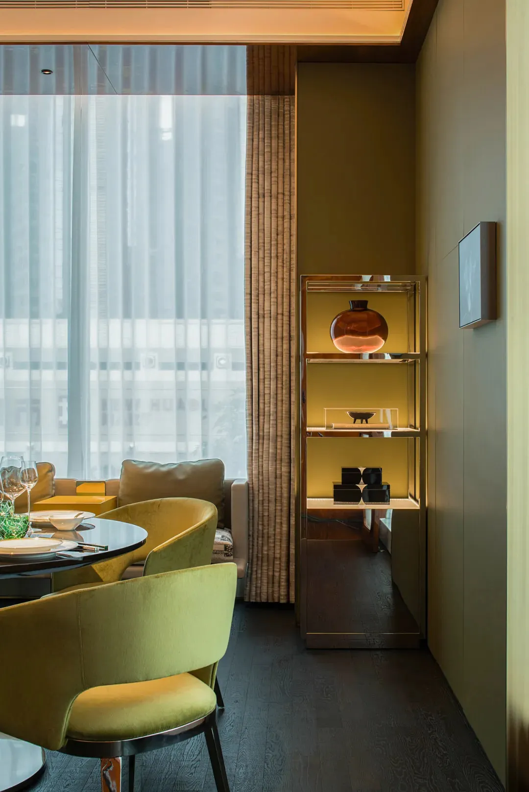 A cozy living space with a yellow chair, dining table, couch, and wine glasses, set in a well-lit studio apartment with a compact furniture arrangement