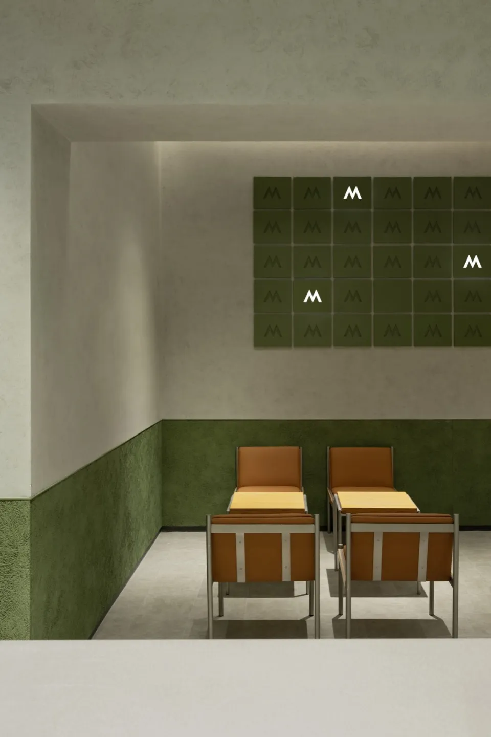 An empty restaurant with two chairs placed in front of a green wall, creating a symmetrical arrangement