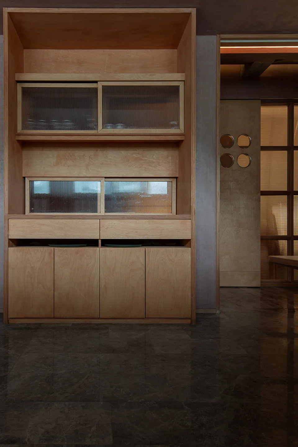 Modern interior design featuring wooden cabinets and drawers with glass doors, providing ample storage solutions in a warm and inviting atmosphere