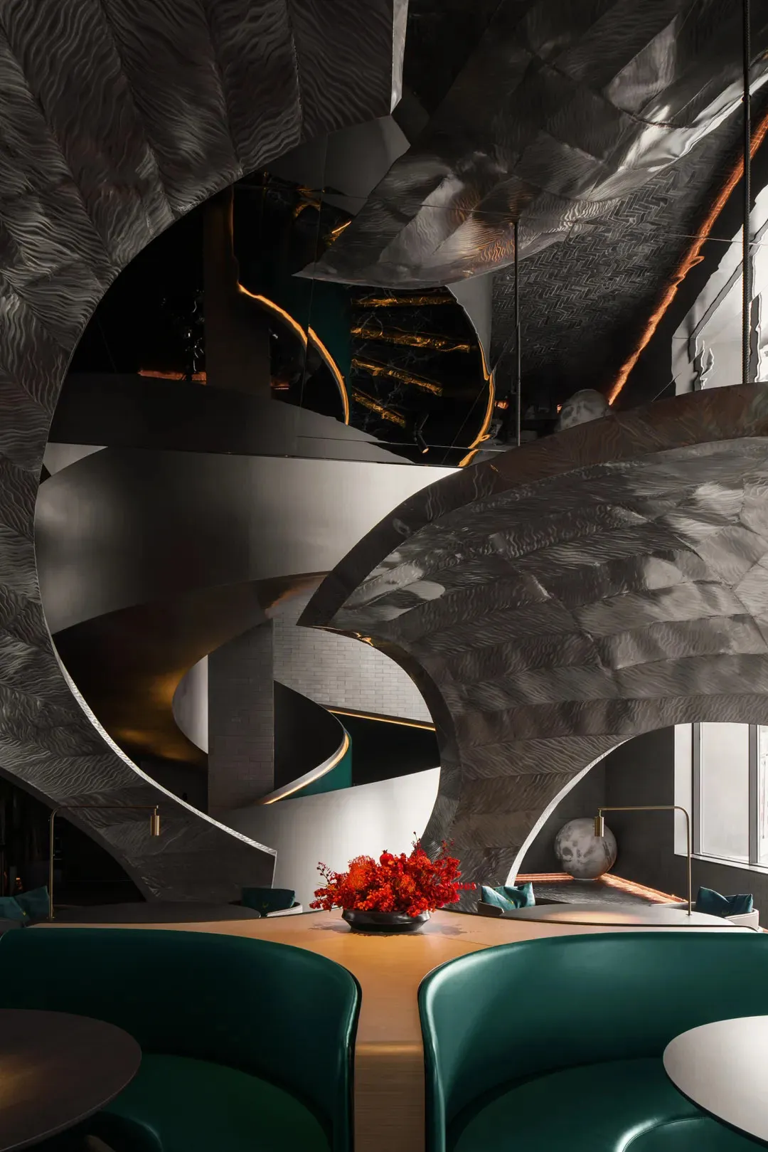 Modern hotel lobby with a spiral metal staircase, a dining table, chairs, and a decorative vase, creating a unique and inviting atmosphere