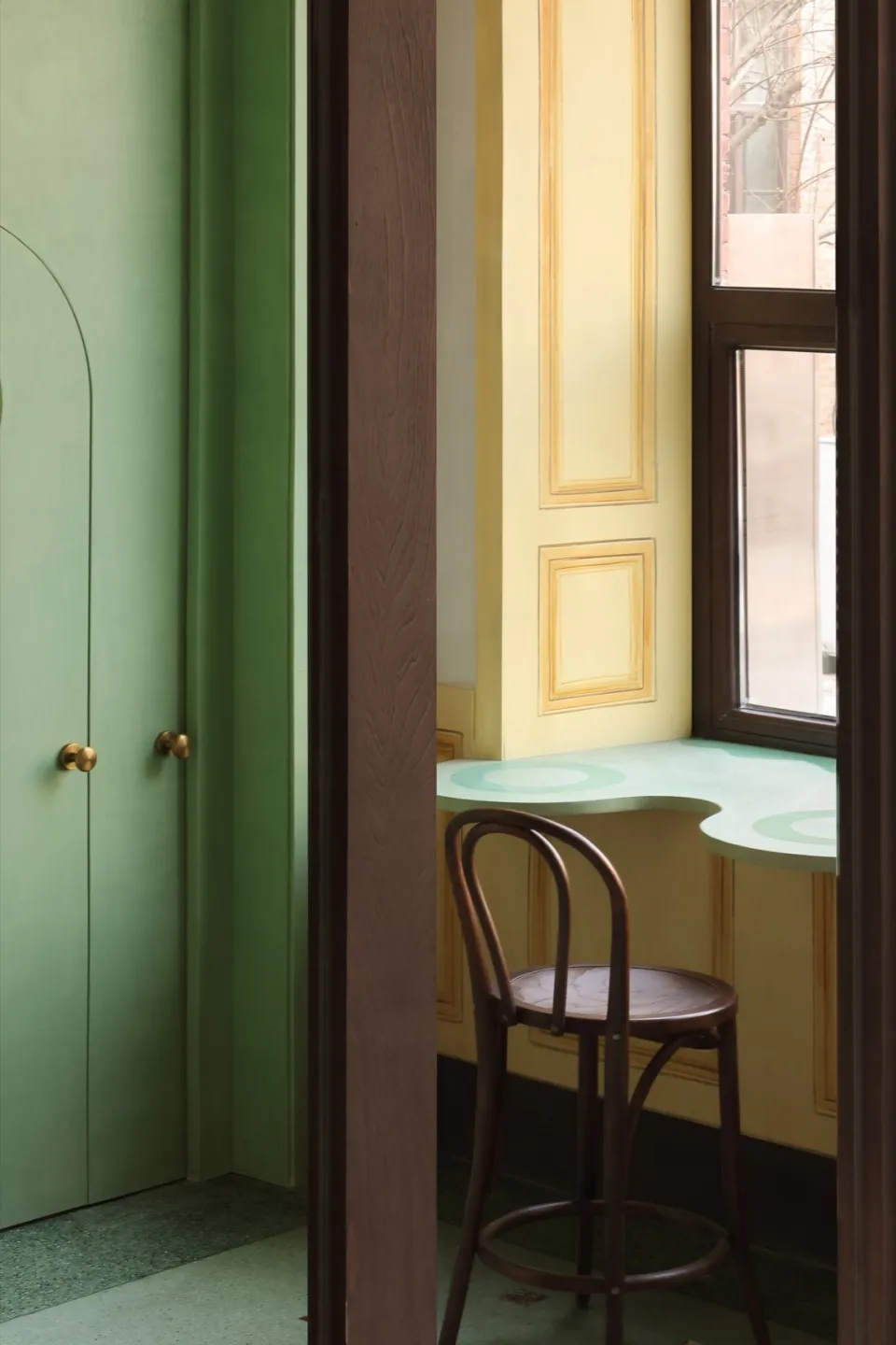 Small room with green walls, yellow trim, two chairs, and a window providing natural light