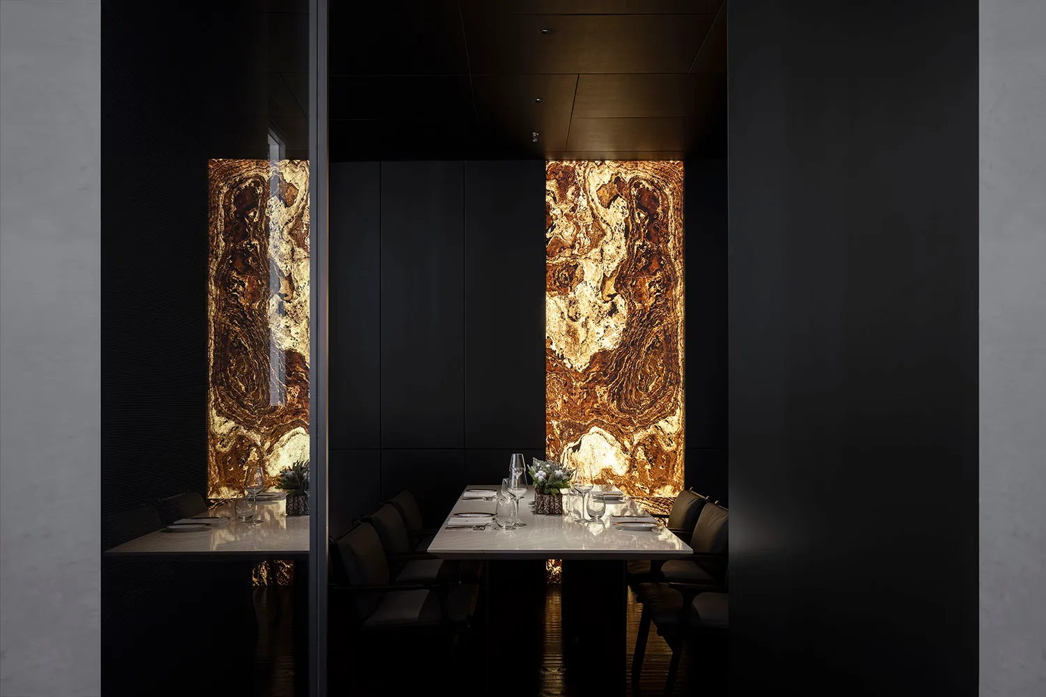Elegant dining space with a black and white theme, featuring a large dining table, chairs, wine glasses, and vases, set in a high-end restaurant