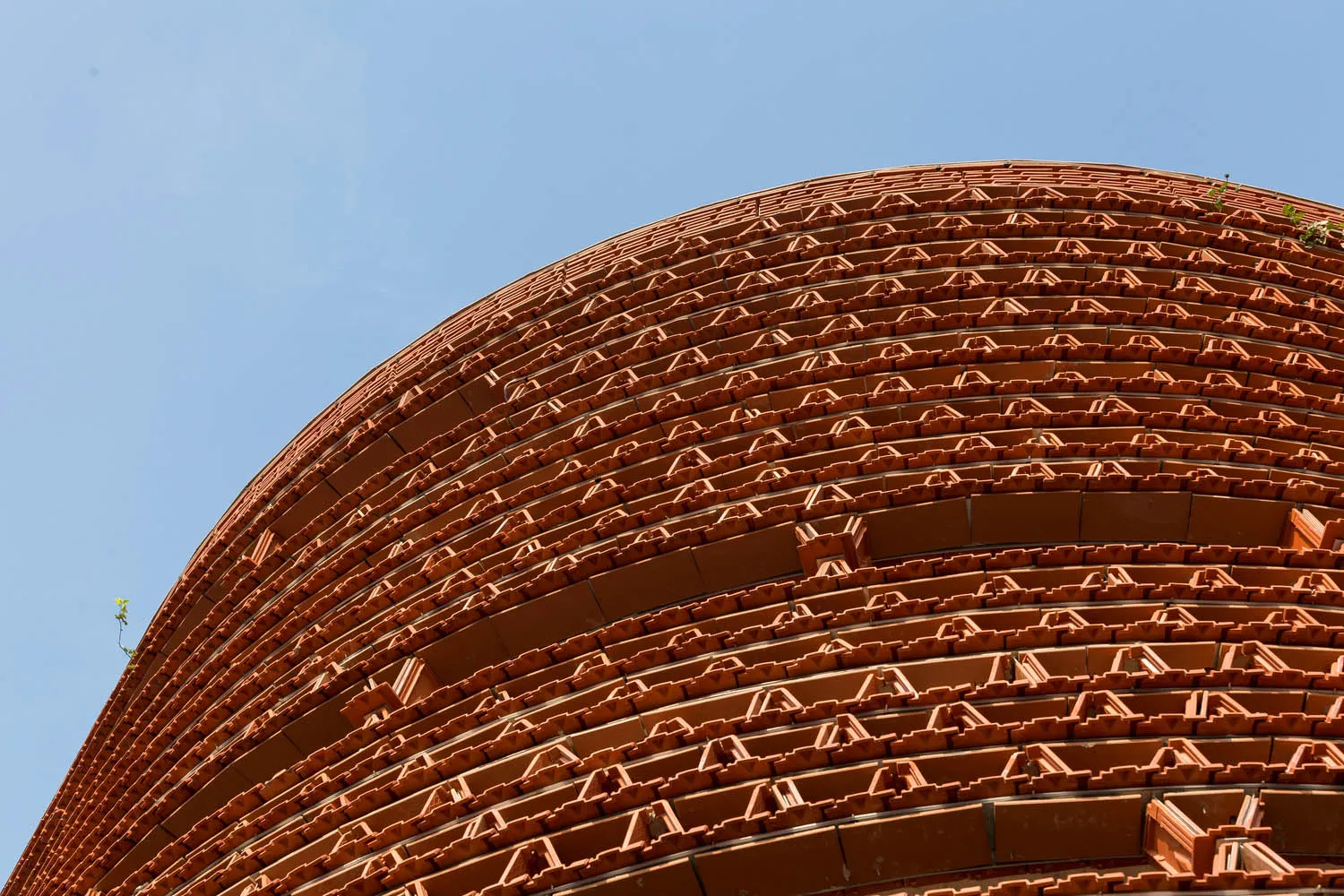 Exterior photo of a modern building with a unique brick design, featuring a mix of red and brown bricks, in a warm and earthy color palette