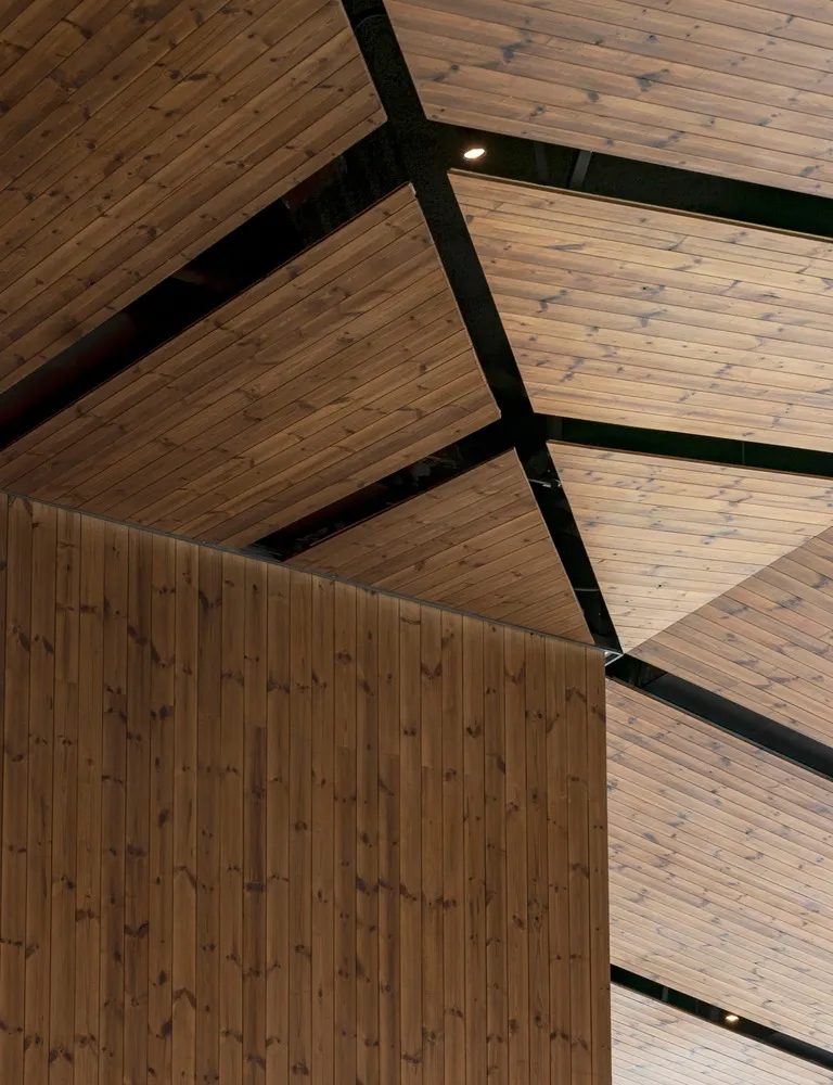 A modern space with exposed wooden beams and ceiling panels, creating a warm and inviting atmosphere with clean lines and simple shapes, well lit by natural sunlight