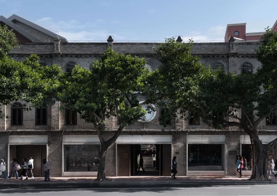 一棟經典磚牆建築前方種有樹木，為都市環境帶來陰涼與自然氣息
