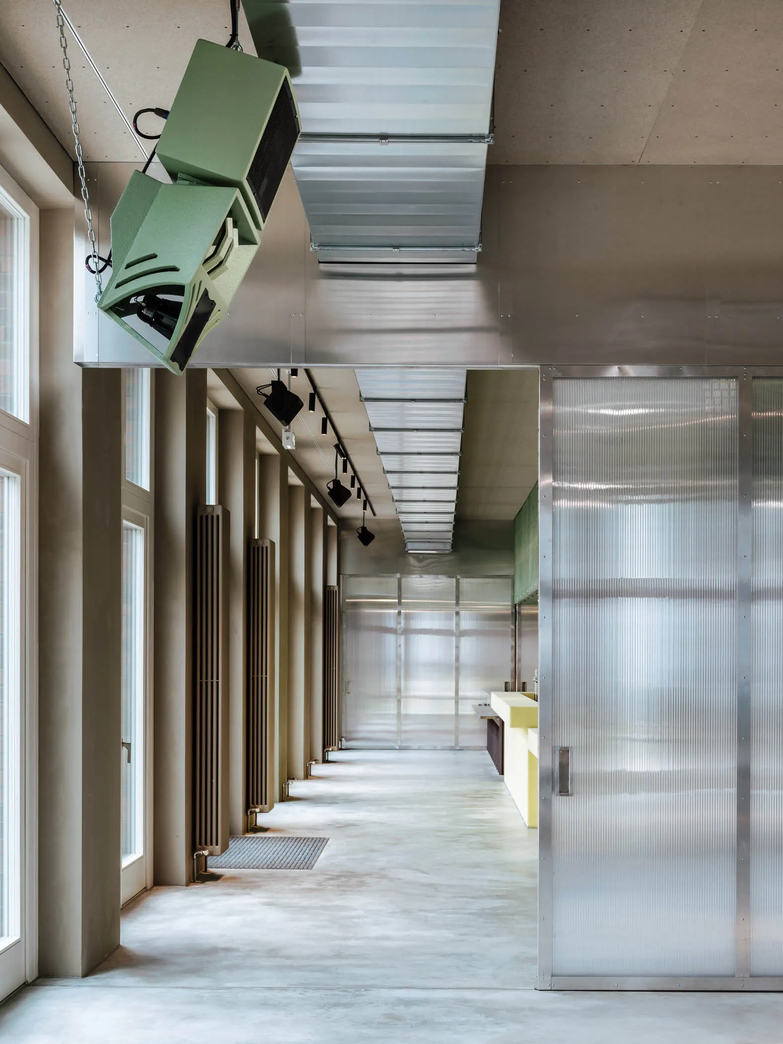 A calm and inviting lobby with a yellow wall, large windows, and concrete walls