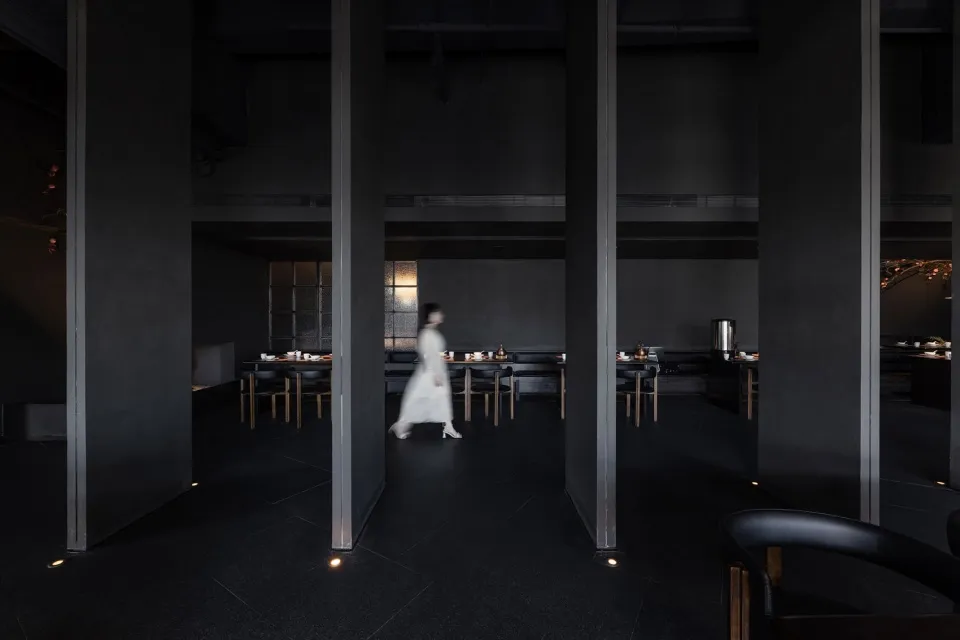 A quiet and inviting restaurant with a black and white theme, featuring dining tables and chairs in a spacious hallway