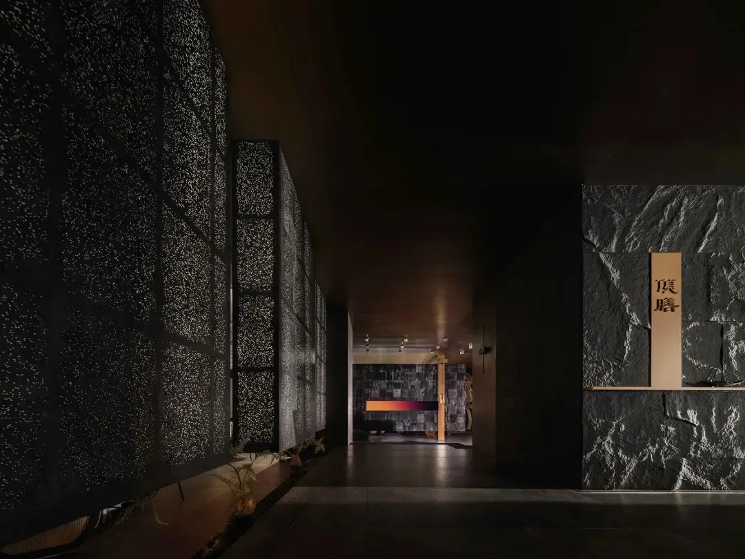 石材牆面與木質牆面的深色室內走廊，設有兩扇窗戶與自然光線
